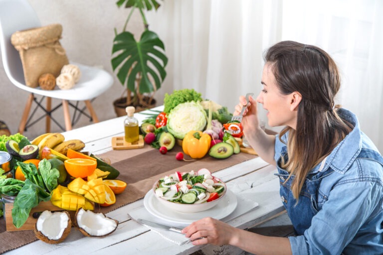 young happy woman eating salad table 1 - „Wspieramy każdego w odkrywaniu i rozwijaniu swojego potencjału, by żyć pełnią życia”