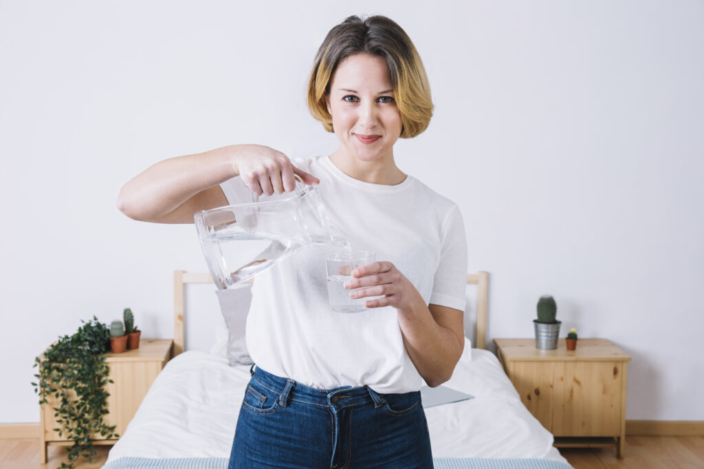 woman pouring water looking camera - „Wspieramy każdego w odkrywaniu i rozwijaniu swojego potencjału, by żyć pełnią życia”